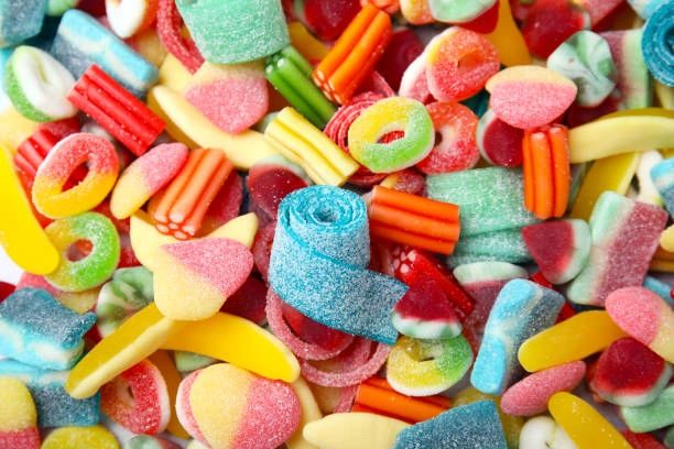 Colorful assortment of sour gummy candies in various shapes and flavors.