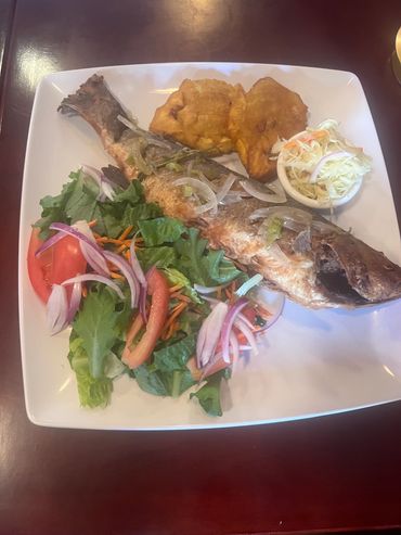 Fried fish meal served with fresh salad, plantains and rice