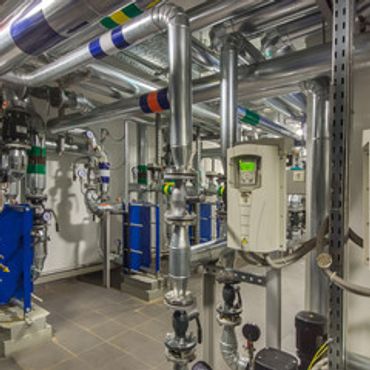 Industrial room with pipes and control units for fluid management.