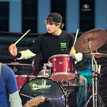 Young drummer playing on a red Premier drum set.