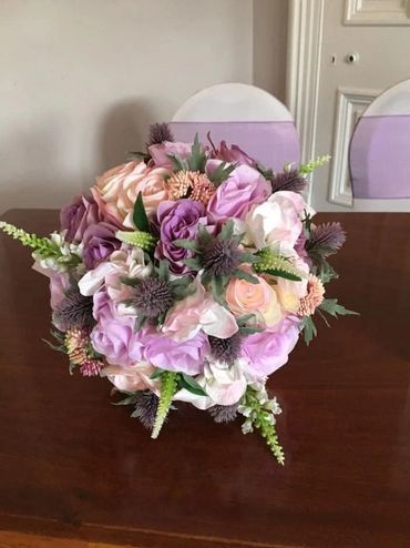 A beautiful bouquet of pastel-colored flowers on a wooden table.