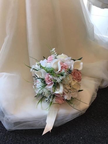 Elegant bridal bouquet with white and pink flowers on a wedding dress.