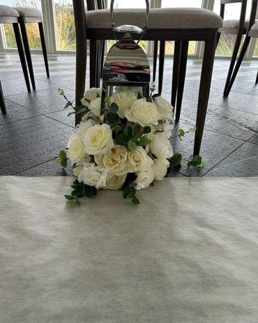 White rose bouquet decoration placed under a chair indoors.
