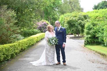 Bride and groom smiling at each other on a garden path.
