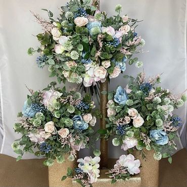 Elegant artificial flower arrangements with pastel roses and blue accents.