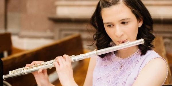 Young woman playing the flute in a church setting.
