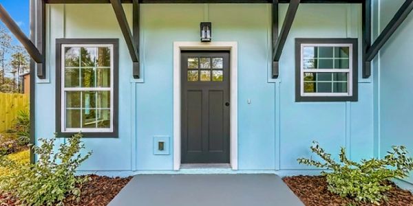Blue house exterior with black door and white-trimmed windows.
