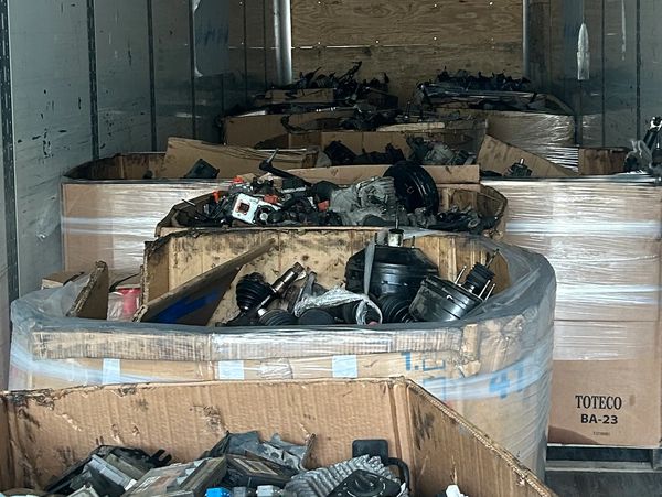 Large cardboard bins filled with automotive parts inside a trailer.