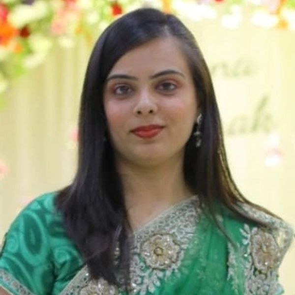 A woman in a green embroidered saree with long black hair.