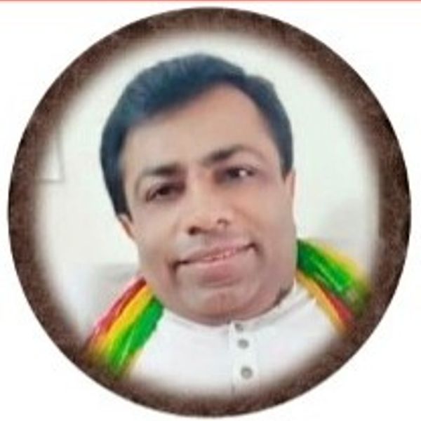 Portrait of a man with a gentle smile, wearing a white shirt and colorful scarf.