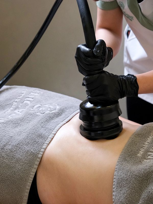 A person receiving a body contouring treatment with a device.