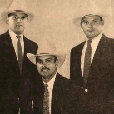 Three men in suits and hats pose for a vintage portrait.