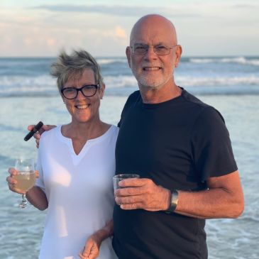 Smiling couple enjoying drinks on the beach at sunset.