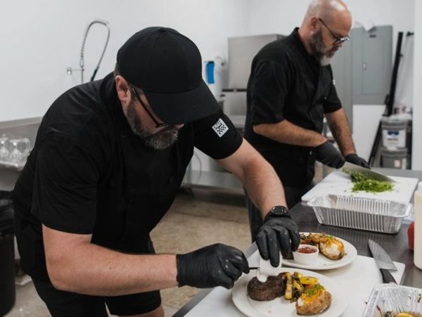 Two chefs preparing meals in a professional kitchen with focused attention to detail.
