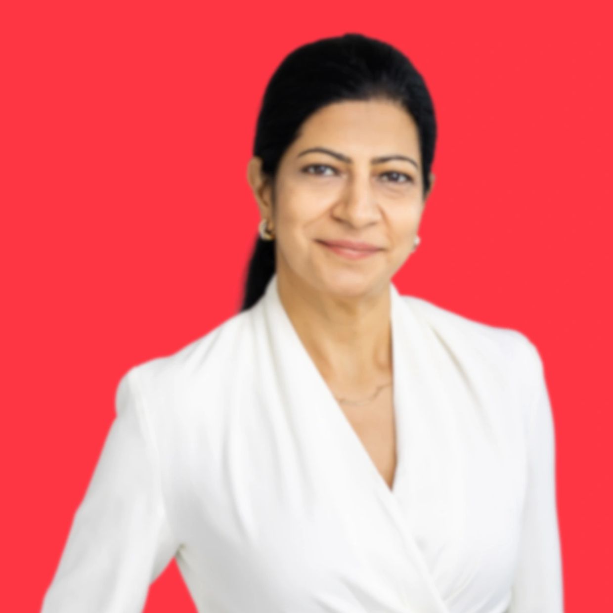 Confident woman in white attire smiling against a red backdrop.