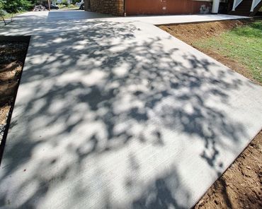 Freshly poured concrete driveway with tree shadows.