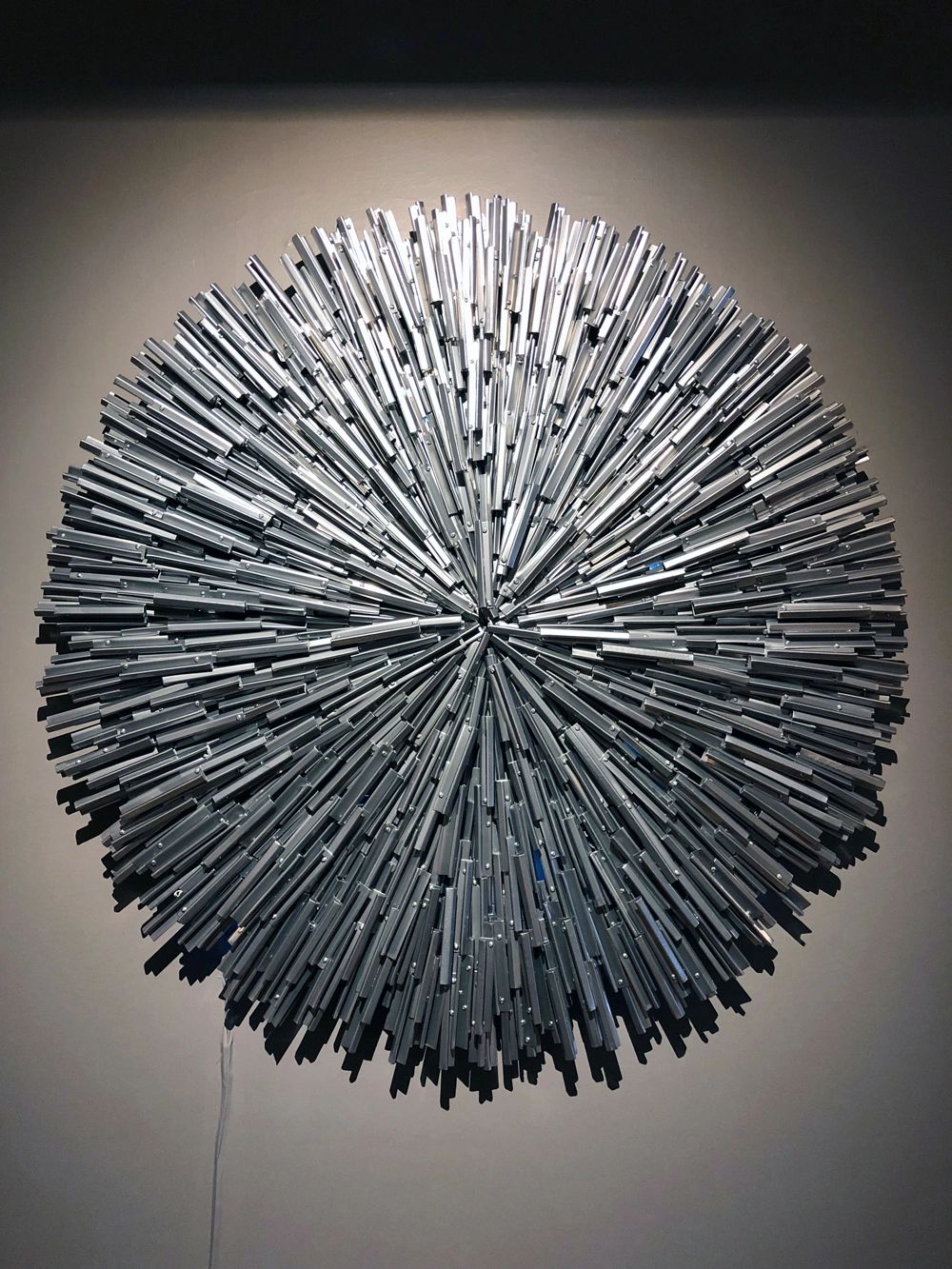 "Astercussion" is a powder coated steel circular sculpture with light radiating from the center.