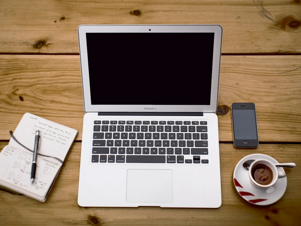 Laptop open with notes next to phone and coffee