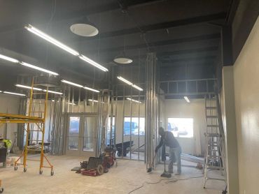 Construction site interior with worker cleaning floor.