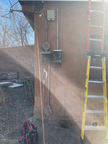 Electrical work setup with open panels, tools, and a ladder.