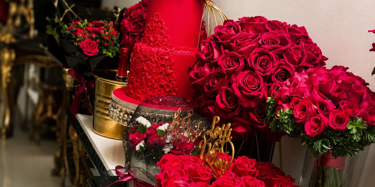 Luxurious red roses and a red cake on an elegant table.