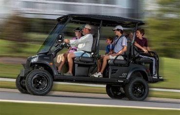 A family riding in a golf cart on a sunny day.