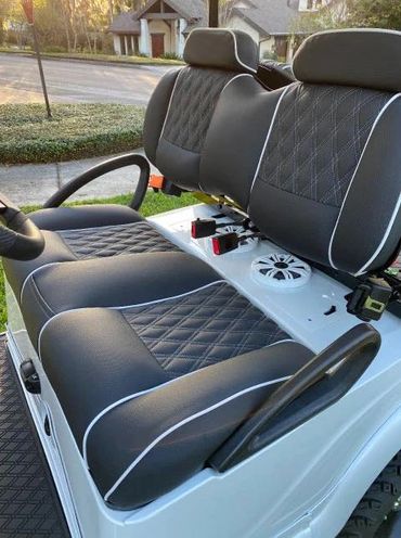 Luxurious black leather seats with diamond stitching on a golf cart.