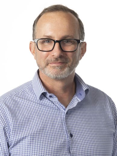 Middle-aged man with glasses and a beard wearing a checkered shirt.