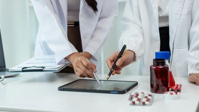 Two doctors discussing medication using a digital tablet.