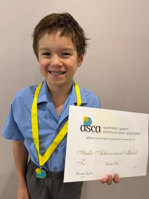 Boy smiling with ASCA medal and certificate.