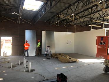 Workers installing insulation panels inside a construction site.