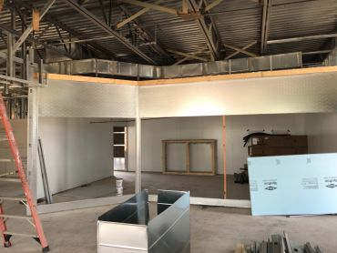 Interior under construction with metal ductwork and tools.