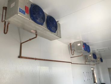Four industrial ceiling-mounted cooling units with blue fans.