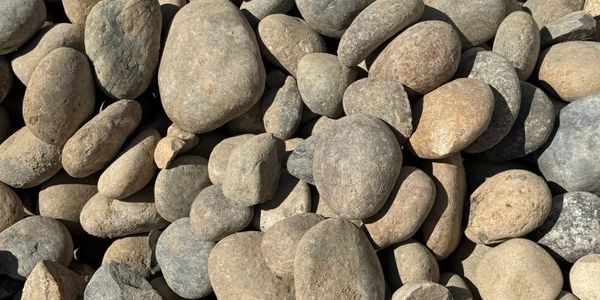 A pile of smooth, round river rocks in neutral tones.