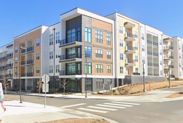Modern multi-story apartment building with balconies under clear blue sky.