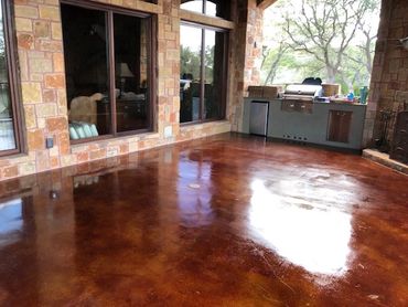 Polished brown concrete floor on an outdoor patio with a grill area.