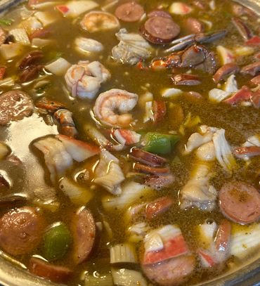 Close-up of a hearty seafood gumbo with shrimp, sausage, crab, and vegetables.