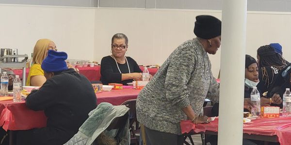 Community members eating and socializing at a gathering with red tablecloths.