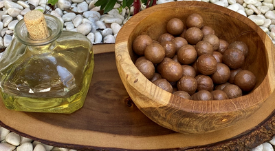 Organic Macadamia nuts and organic, cold-pressed Macadamia nut oil displayed on a wooden tray
