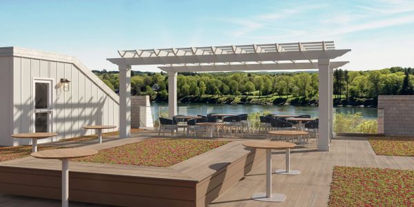 A rooftop terrace with tables, chairs, pergola, and a scenic river view.