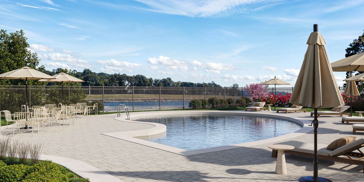 Outdoor pool area with lounge chairs and umbrellas overlooking a lake.
