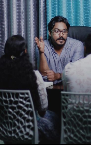Man with glasses explaining something to two people in a meeting.