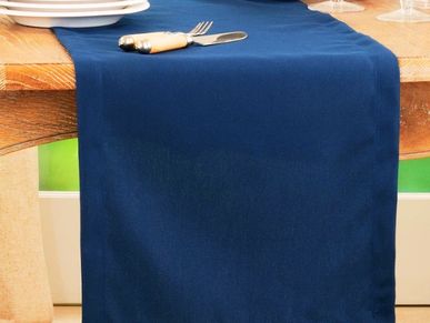 A wooden table with a blue table runner and cutlery on top.