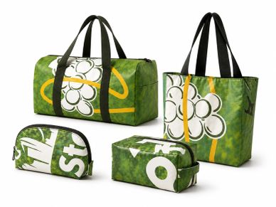 Set of four green bags with white floral patterns and black handles.