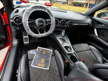 Audi car interior with cleaning service flyer on seat.