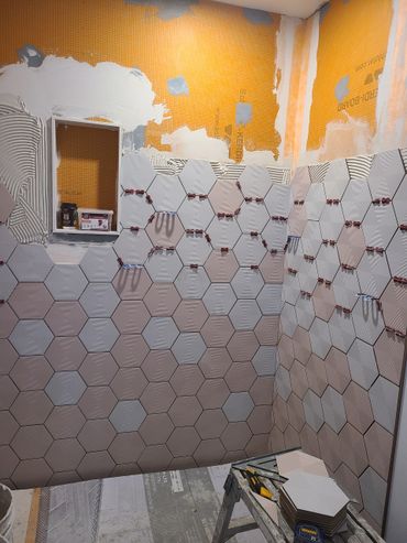 Hexagonal tiles being installed on bathroom walls during renovation.