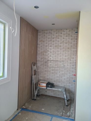 Partially tiled room with wooden panels and construction tools.