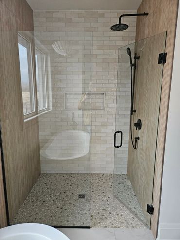 Modern shower with pebble floor and glass door.