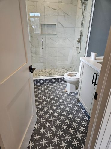 Modern bathroom with patterned floor tiles and marble shower walls.