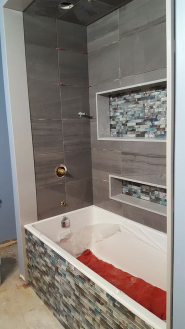 Modern bathtub with gray tiles and blue mosaic accents.